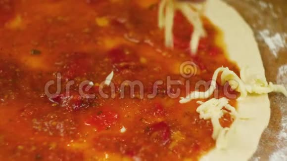 做披萨厨师把奶酪和罗勒放在比萨饼的底部涂上番茄酱男女订婚视频的预览图
