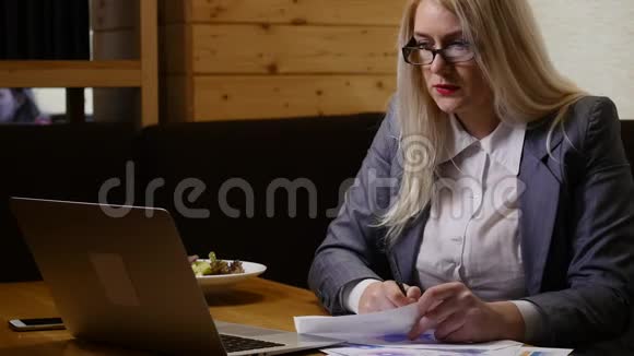 年轻女商人在咖啡馆里拿着笔记本电脑和文件视频的预览图