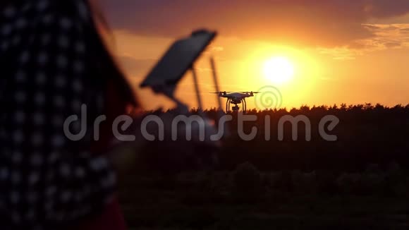 年轻女子在日落时分用一个面板来管理她的无人机视频的预览图