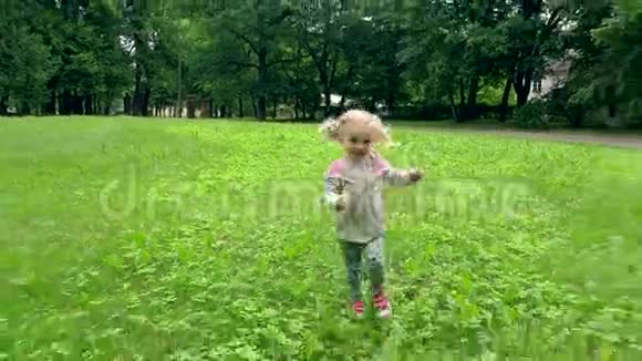 小女孩在公园里穿过草地快乐的孩子在户外玩视频的预览图