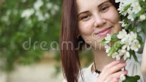 公园里一棵开花树附近的美丽女孩肖像青春和自然美的概念一个年轻的女孩视频的预览图