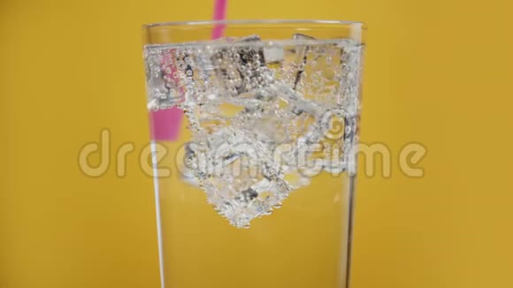 将冷水饮料与粉红色饮用吸管混合盛满泡沫冰块的玻璃视频的预览图