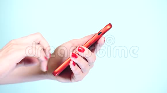 特写红色美甲的女性手在彩色背景上使用智能手机4k慢镜头拍摄视频的预览图