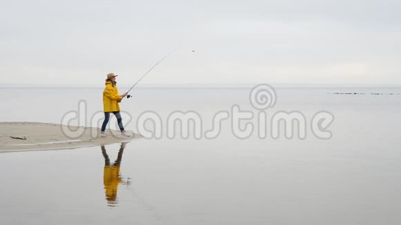 穿黄色雨衣的女渔夫用旋转杆慢动作投掷渔具视频的预览图