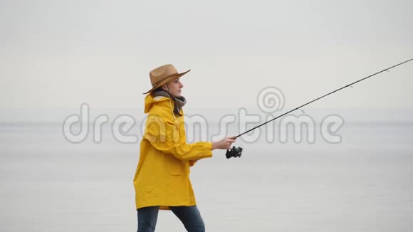 穿黄色雨衣的女渔夫用旋转杆慢动作投掷渔具视频的预览图