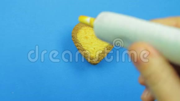 一只雌性的手在蓝色的背景上画出有趣的脸蓝色的心形饼干上有一管棕色的糖霜视频的预览图