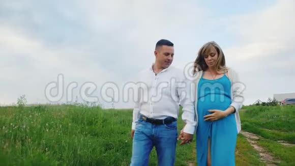 Stedicam拍摄年轻夫妇丈夫和怀孕的妻子在日落时分穿过乡村视频的预览图