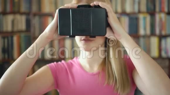 快乐的学生站在图书馆使用虚拟现实眼镜背景书架视频的预览图