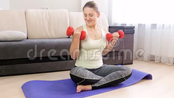 4k镜头美女在家里健身垫上用哑铃锻炼视频的预览图