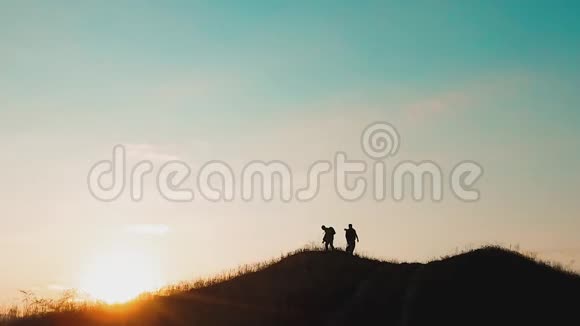 两个男游客徒步者剪影去山日落旅游慢动作视频旅行成功的年轻人视频的预览图