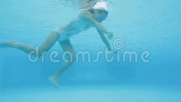 年轻的金发女子在游泳池里表演水下倒立视频的预览图