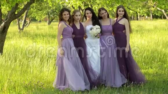 情绪化的新娘和伴娘说话微笑穿紫色裙子在户外摆姿势的白人女孩视频的预览图