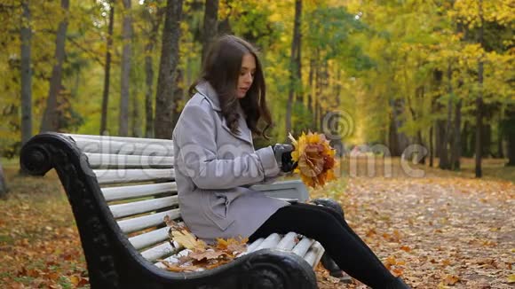 快乐的年轻女人坐着一束叶子微笑嬉戏视频的预览图
