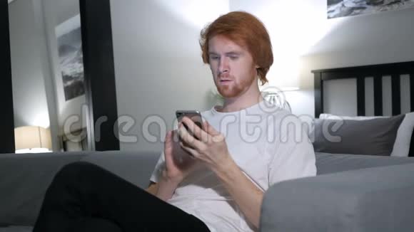 红发男子在使用智能手机时兴奋不已视频的预览图