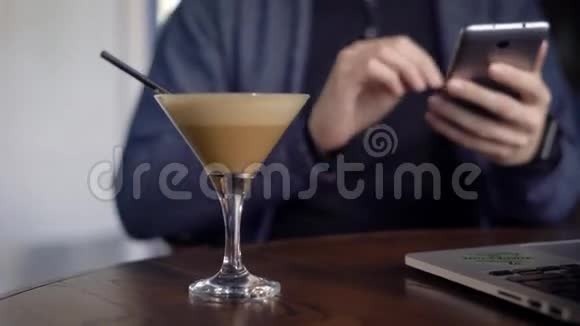 用智能手机和喝鸡尾酒把坐在桌旁的人关起来流动工作的自由职业者视频的预览图
