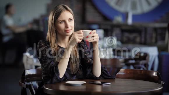 一个金发碧眼的好女人坐在餐馆里望着远处享受着一杯热咖啡视频的预览图