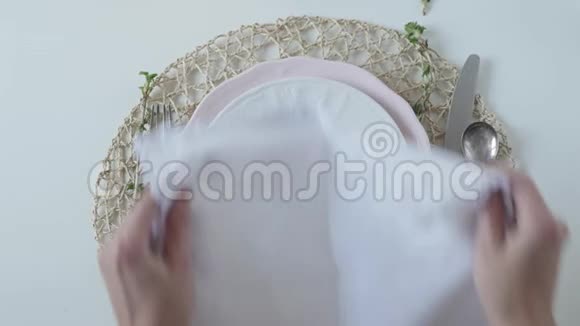 桌子设置白色背景上的白色菜肴那个女人把餐巾漂亮地叠在盘子里优雅的餐桌视频的预览图