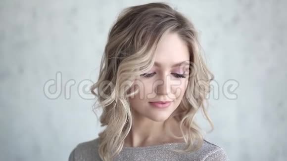 一张漂亮金发女郎的特写照片化着淡妆卷发的年轻女孩视频的预览图