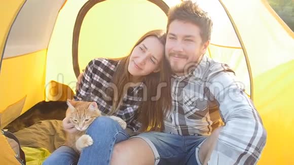 在徒步旅行中一对猫坐在帐篷里的小幸福夫妇视频的预览图