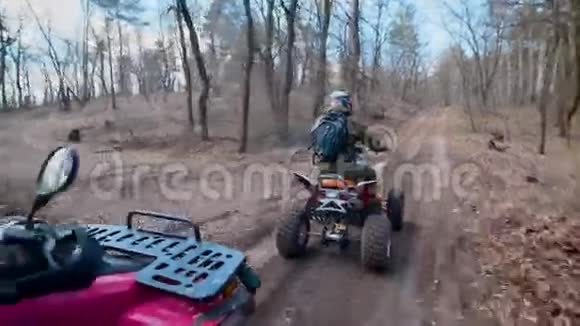 两个男性朋友驾驶ATV在森林里一个接一个地沿着道路移动骑手们正在旅行视频的预览图