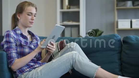 坐在沙发上的女人在平板电脑上在线视频聊天视频的预览图