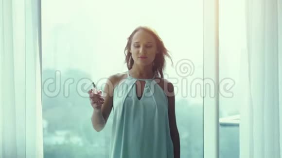 迷人的少女睡衣在城市景观的气窗背景上喷着香水视频的预览图