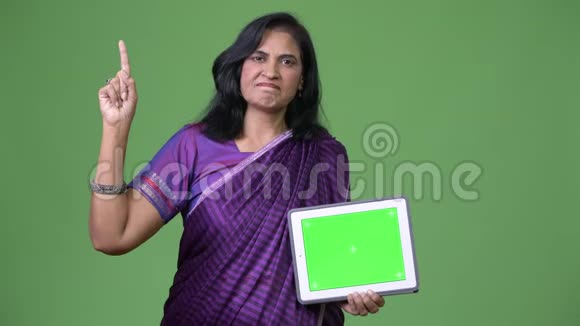 成熟美丽的印度女人展示数字平板电脑手指视频的预览图