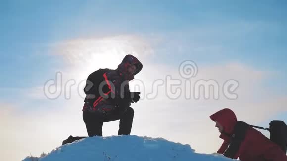 团队合作两个旅游徒步旅行者伸出了援手成功赢得冬天到达山顶游客登山视频的预览图