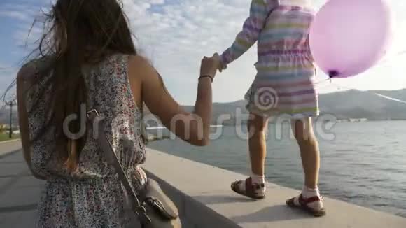 早上女人和一个美丽的小女孩在海滨散步视频的预览图