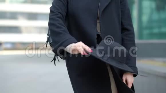 女人玩现代黑色帽子移动宽边起首在黑色外套底部在街道慢动作低角度拍摄视频的预览图