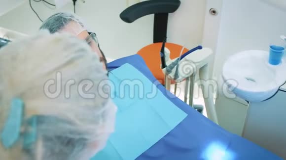 健康和牙科护理妇女在工作中担任牙医和医生与男性病人交谈讨论牙科治疗视频的预览图