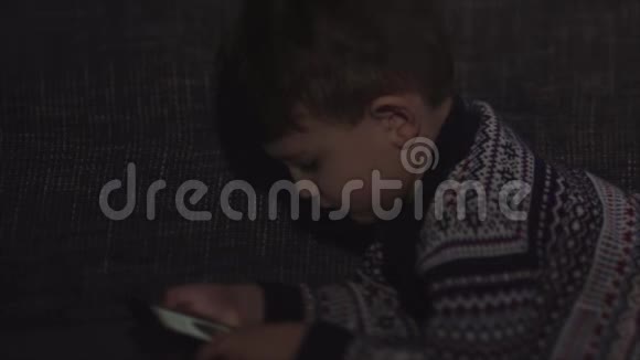 可爱的男孩坐在客厅的沙发上玩小玩意幼儿学习如何使用智能手机视频的预览图