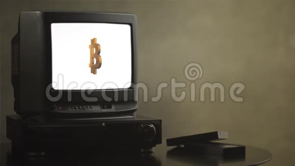 木制桌子上的老式电视和比特币旧电视显示比特币电视附近有电影磁带和录像视频的预览图