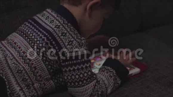 可爱的男孩坐在客厅的沙发上玩小玩意幼儿学习如何使用智能手机视频的预览图