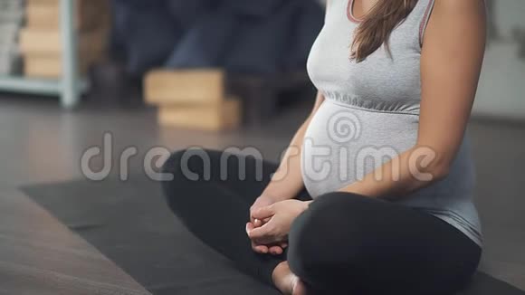 一位孕妇坐在莲花的位置特写双手视频的预览图