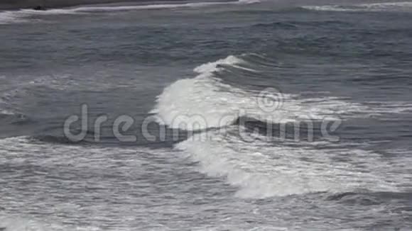 热带海洋的海岸在阳光明媚的日子里海浪在海岸上用黑色的石头奔跑缓慢的运动视频的预览图