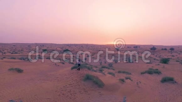美丽的女孩在沙漠中跳舞背景是阳光快乐美丽的女人在日落时在沙滩上跳舞视频的预览图