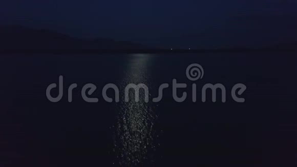 无人驾驶飞机夜间在湖面反射的月球上空飞行视频的预览图