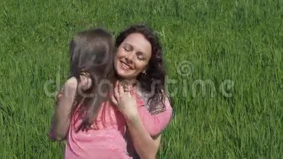 妈妈在大自然中拥抱孩子在草地上的公园里有小女孩的女人家人在草坪上拥抱视频的预览图