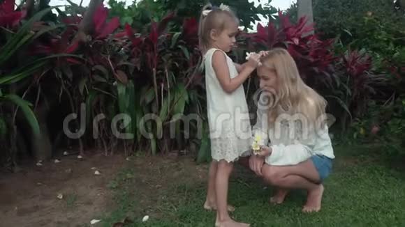 小女孩用鸡蛋花装饰母亲的头发慢镜头视频视频的预览图