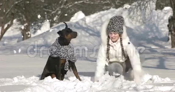快乐的女孩在雪地上玩她的狗在冬天的外面玩得很开心视频的预览图