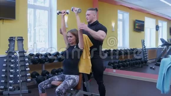 她的私人健身教练在健身房和杠铃一起锻炼视频的预览图