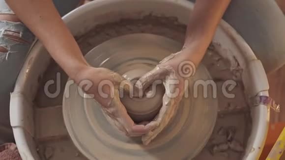双手放在黏土里轻轻地触摸陶工车轮上的身影视频的预览图
