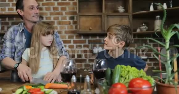 一家人在厨房里用平板电脑的食谱一起做饭父母带着两个孩子在视频的预览图