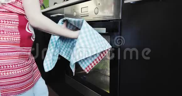 一个穿红色围裙的金发女孩从烤箱里拿出一个热馅饼视频的预览图
