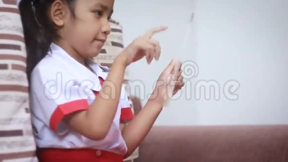 幼儿园小女孩泰国学生制服使用透明玻璃平板电脑未来网络技术概念视频的预览图