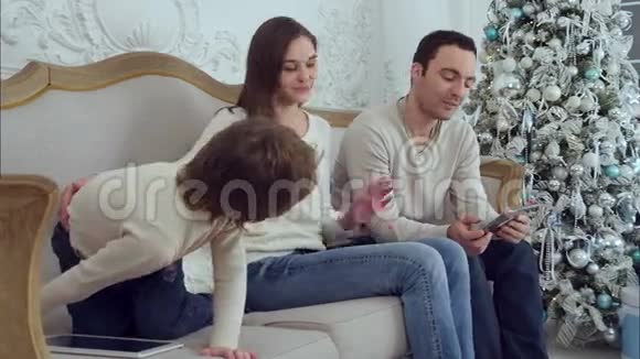 年轻的妈妈和她精力充沛的小儿子玩爸爸则用平板电脑视频的预览图