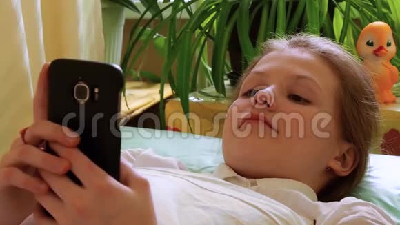 小女孩用智能手机笑着看着躺在病床上视频的预览图