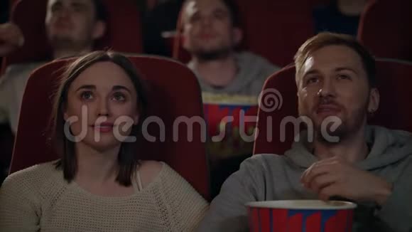 年轻人在电影院欣赏电影两个人吃爆米花看电影视频的预览图