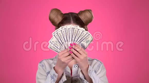 女孩拿着纸钞眨眼粉色背景视频的预览图